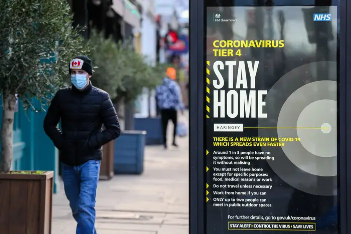 A man wearing a protective face covering in north London walks past the government's 'Coronavirus Tier 4 - Stay Home' publicity campaign poster, after the mutated variant of the SARS-Cov-2 virus continues to spread around the country.